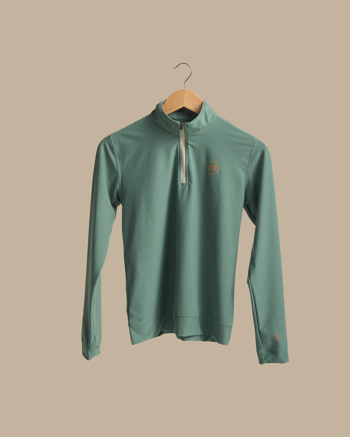 A green women's pullover with a high collar and a small logo on the chest area, displayed on a wooden hanger.